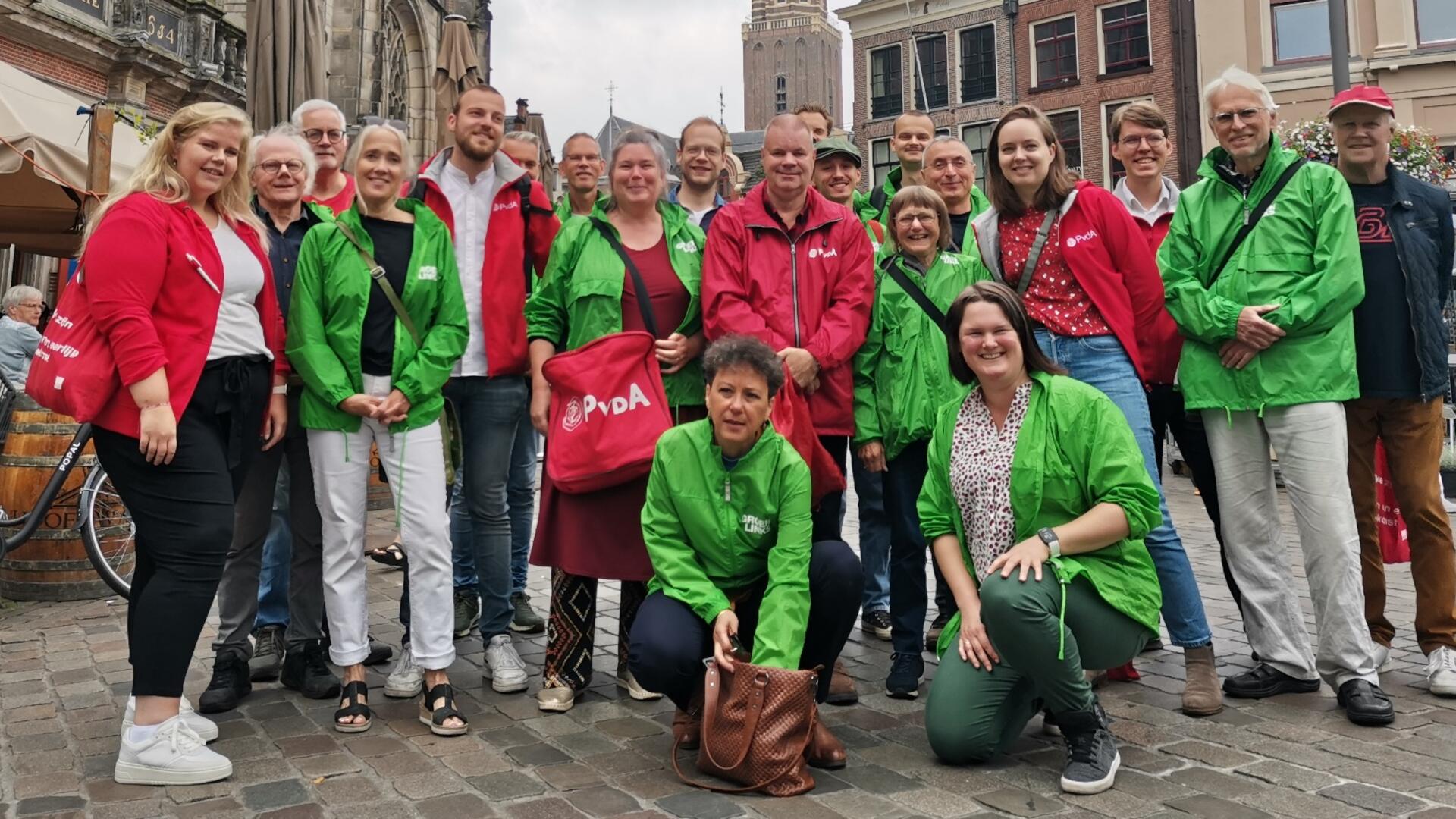 Een groep vrijwilligers van PvdA en GroenLinks met rode en groene jasjes aan.