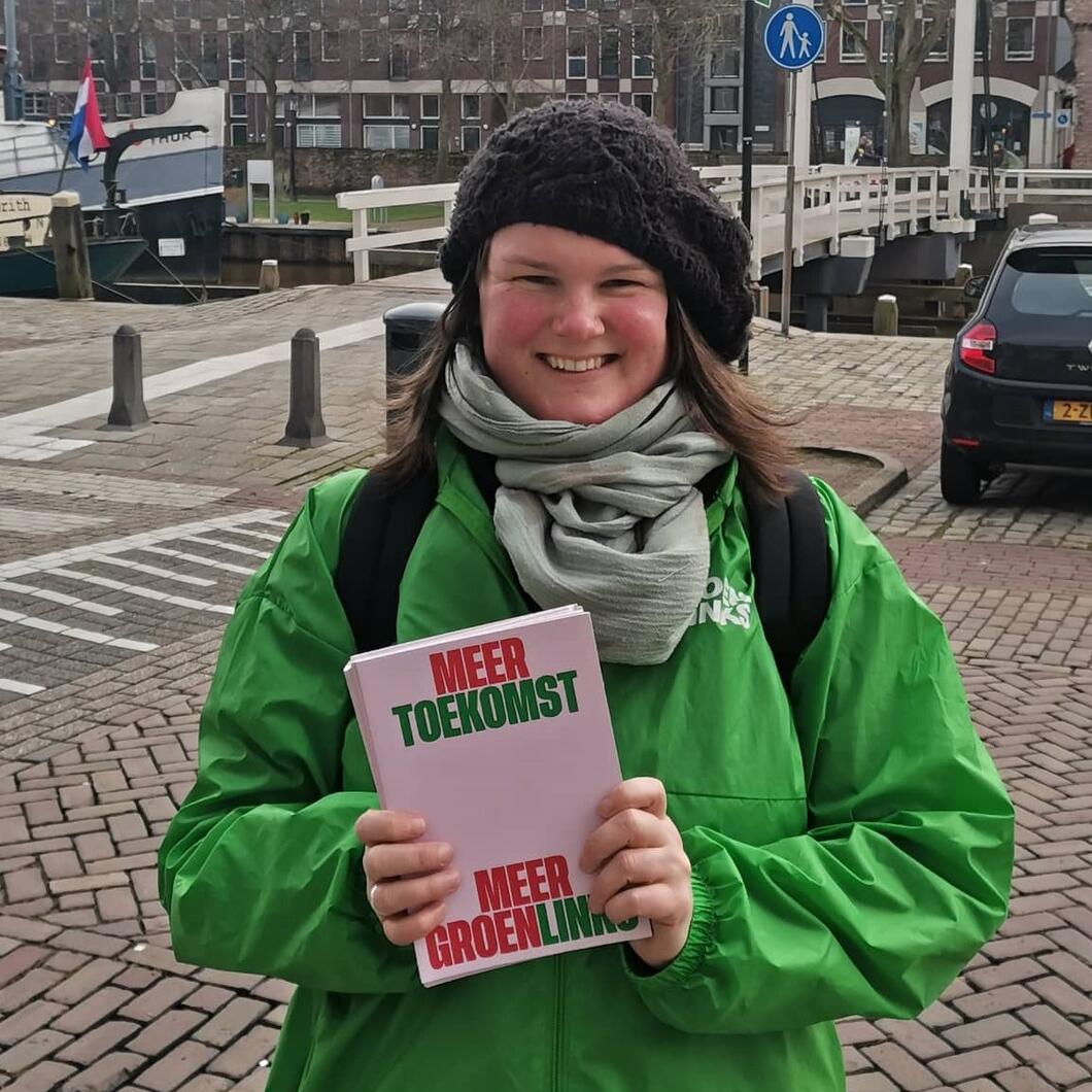 Judith van Dijk met GroenLinks-jasje en en campagneflyer