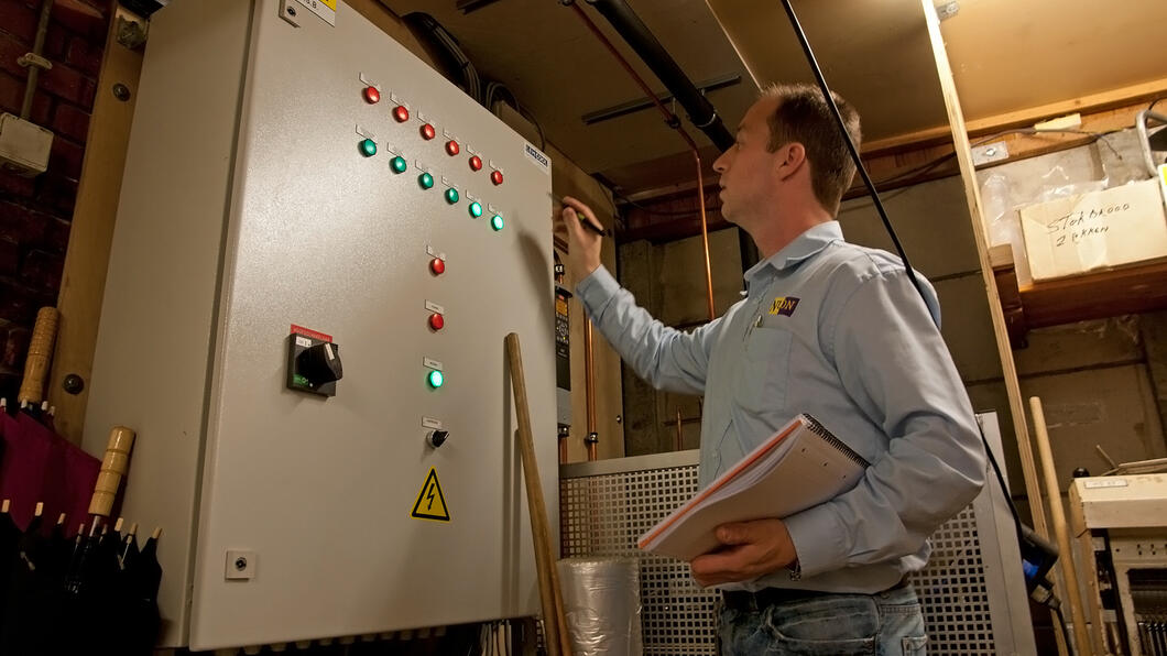 Een man controleert de afstelling van een verwarmingsapparaat