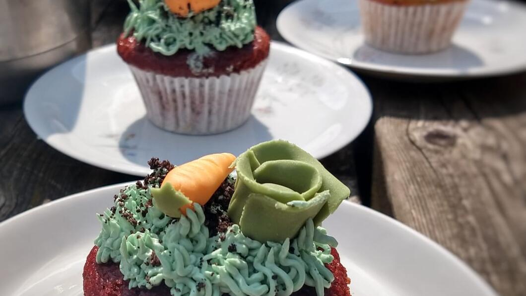 Cupcakes op bordjes op tafel. Elke cupcake is versierd met groenten van fondant.