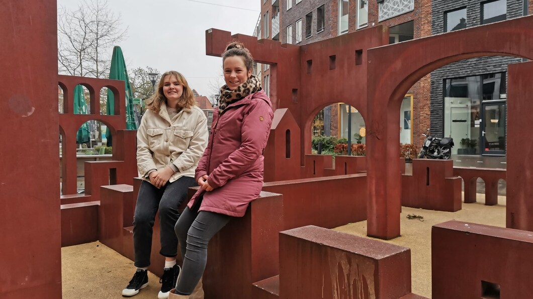 Aniek en Simone zitten op een kunstwerk van metaal