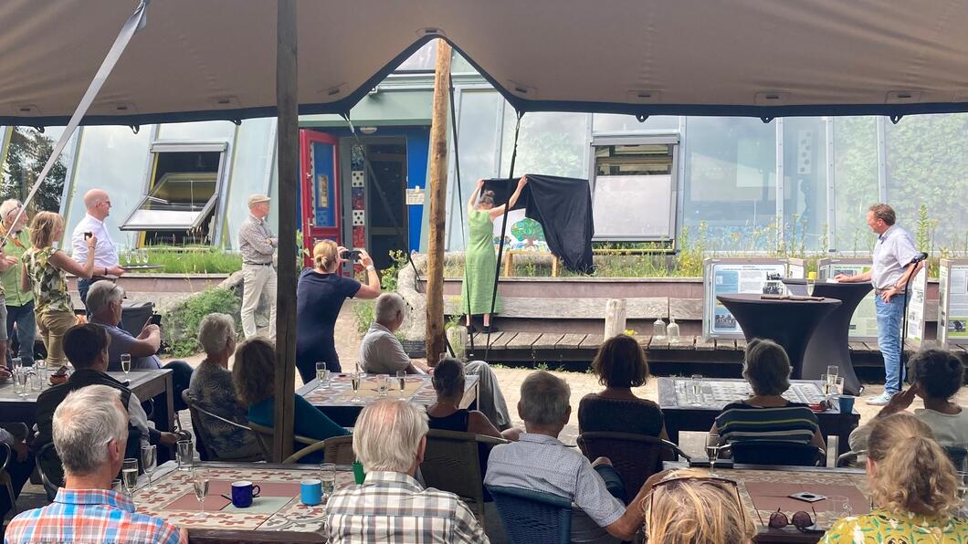 Een terras vol mensen kijkt naar de onthulling van het nieuwe logo van de Nooterhof