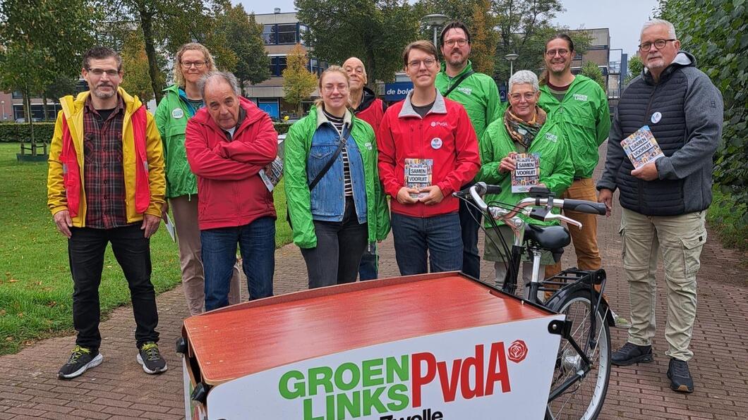 Een groep vrijwilligers met rode en groene jasjes aan