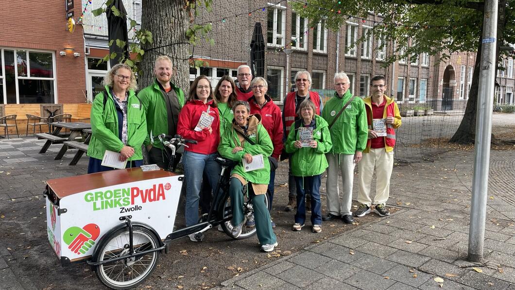 Een groep vrijwilligers met rode en groene jasjes aan