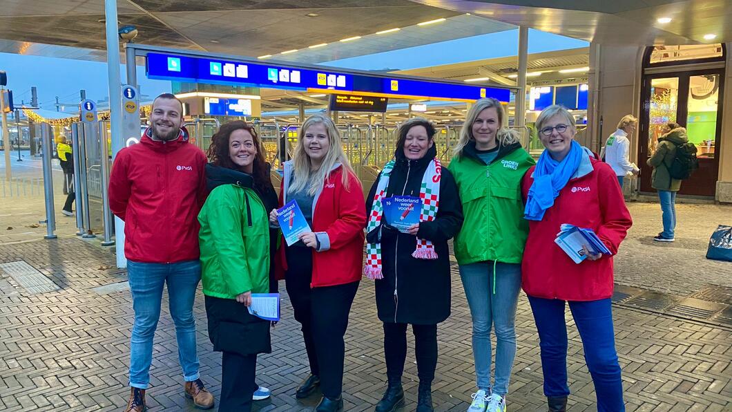 Een groep vrijwilligers met rode en groene jasjes aan
