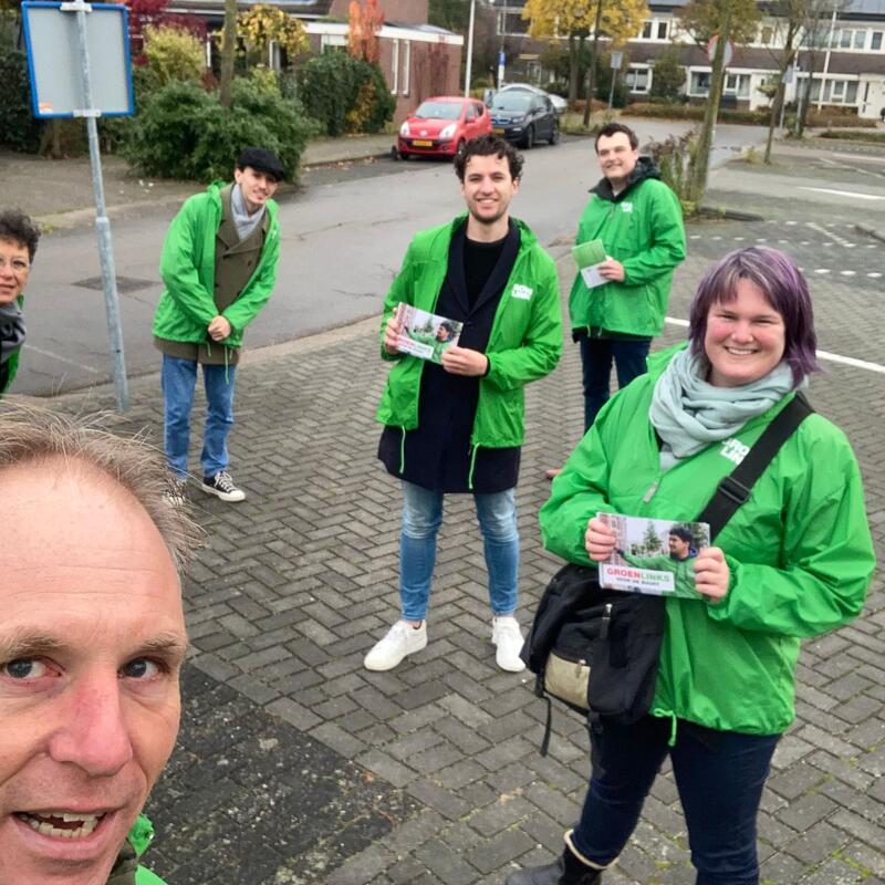 Een groep vrijwilligers met groene jasjes aan.