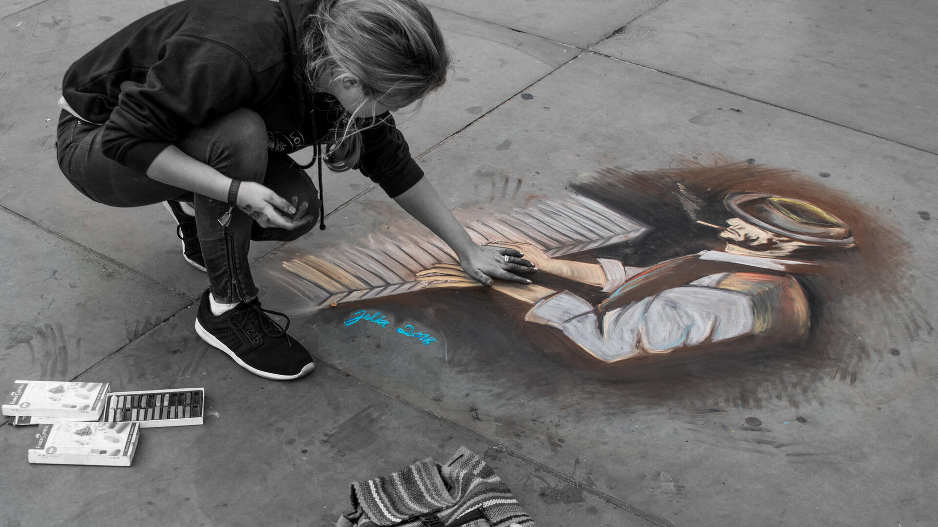 Een straatartieste maakt op straattegels een tekening van een pianist.