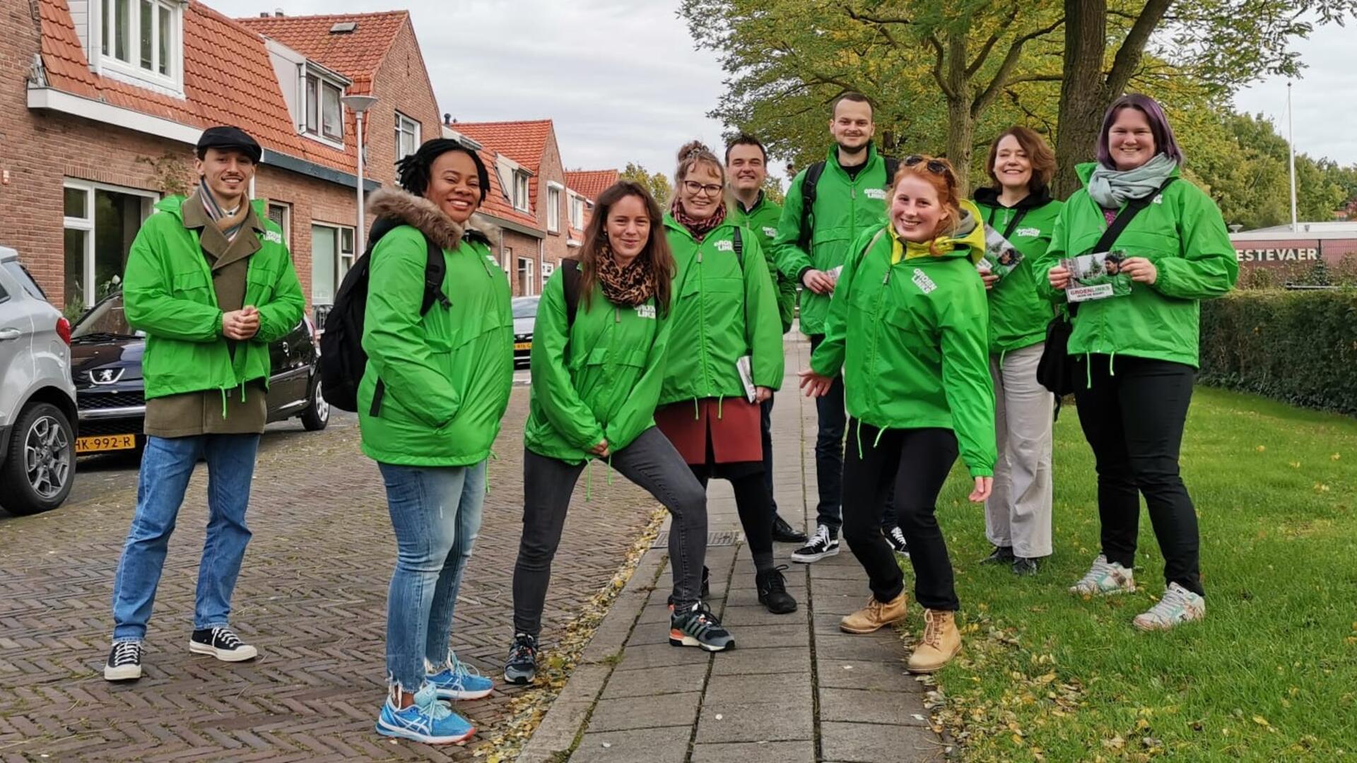 Een groep vrijwilligers met groene jasjes aan.