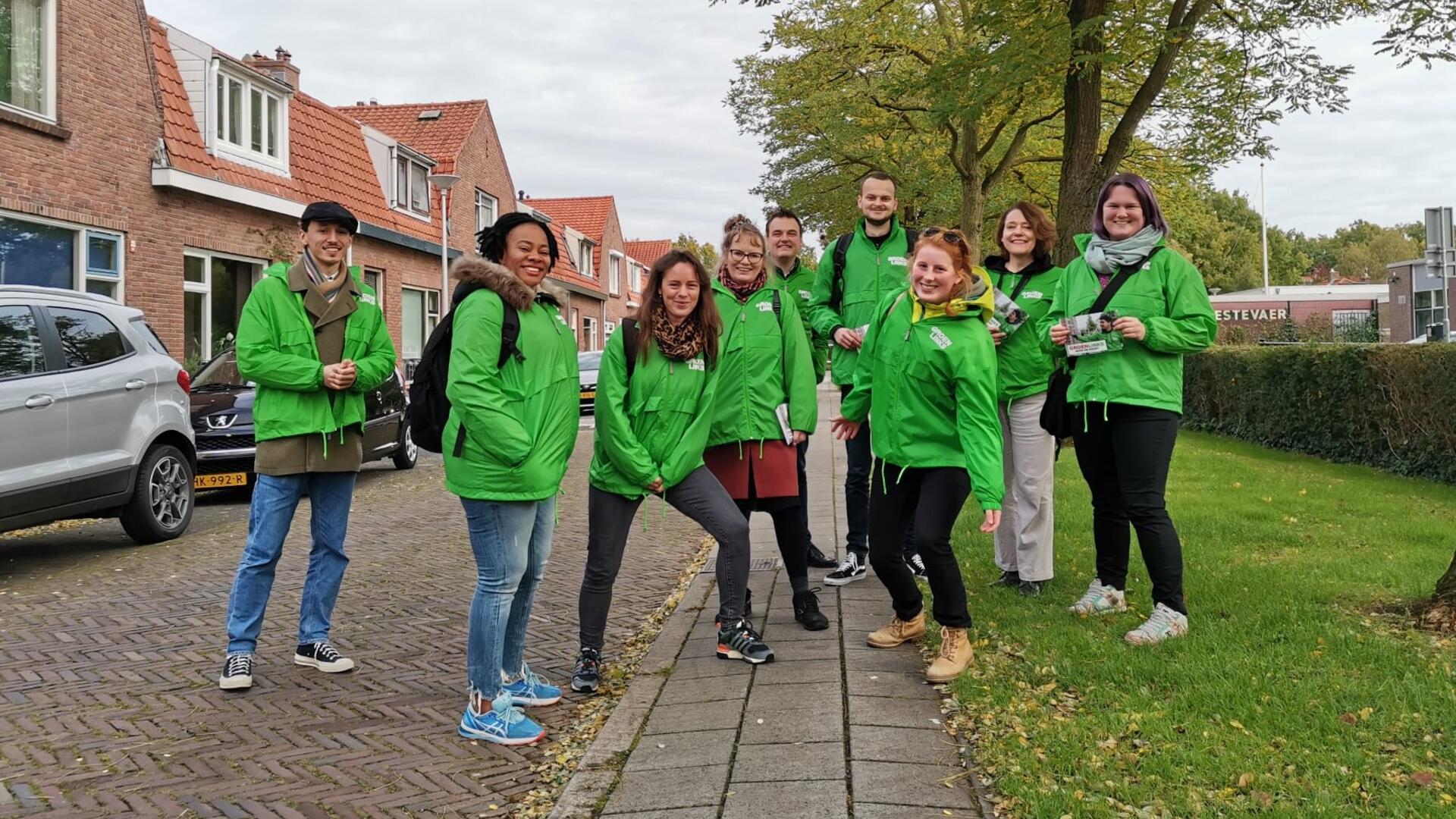 Een groep vrijwilligers met groene jasjes aan.