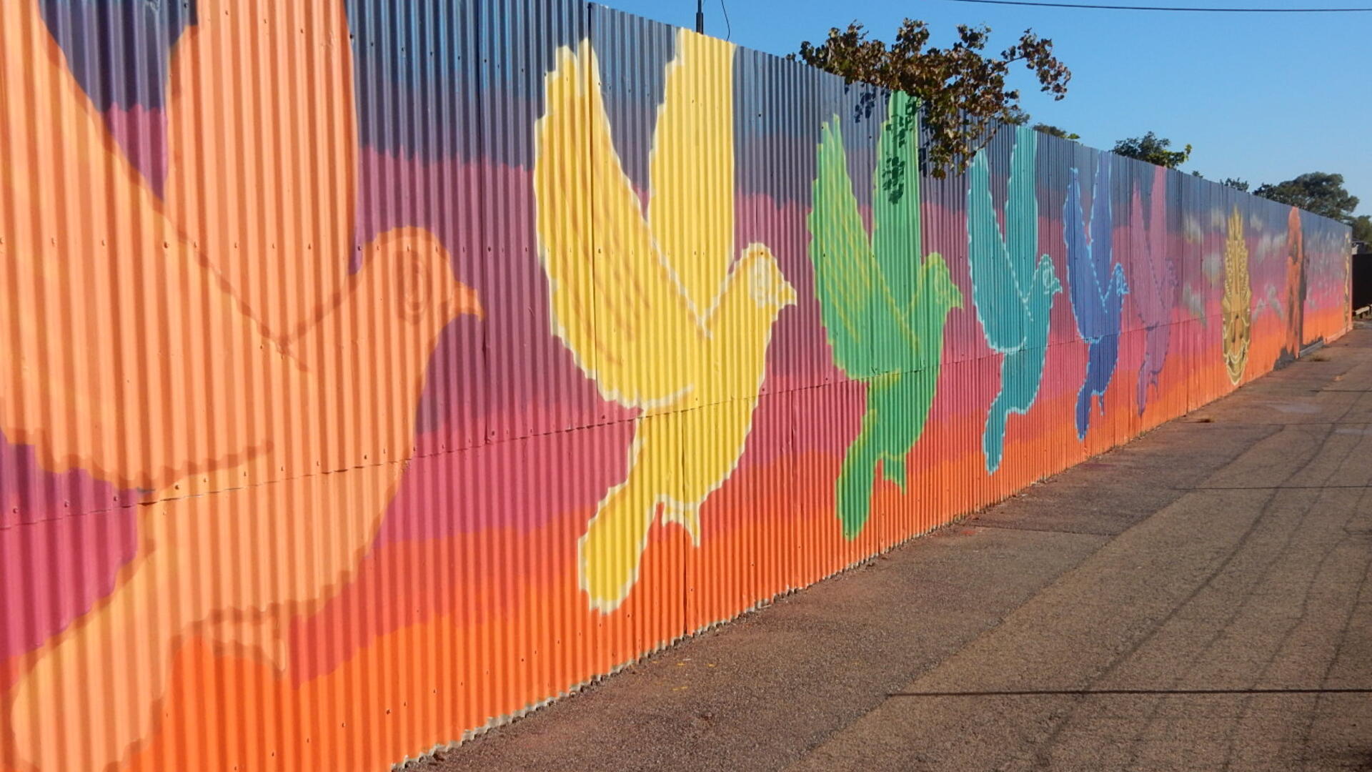 Een muur met daarop duiven geschilderd in verschillende kleuren