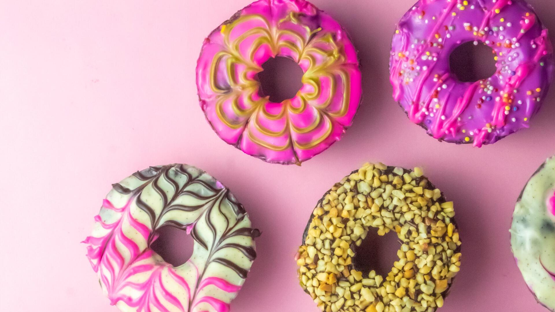 Verschillende gedecoreerde donuts voor een roze achtergrond