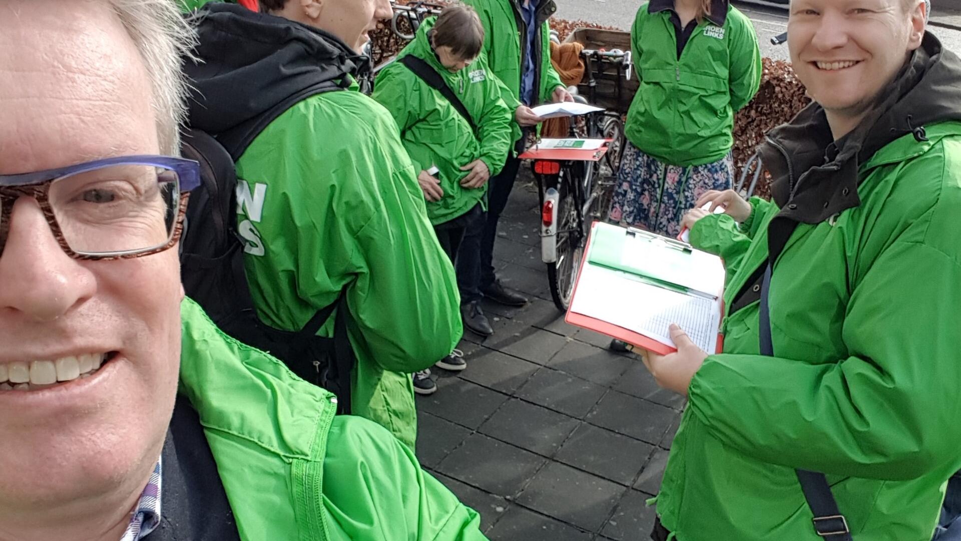 Remko de Paus maakt een selfie. Hij heeft net als andere GroenLinks-vrijwilligers een groen jasje aan.