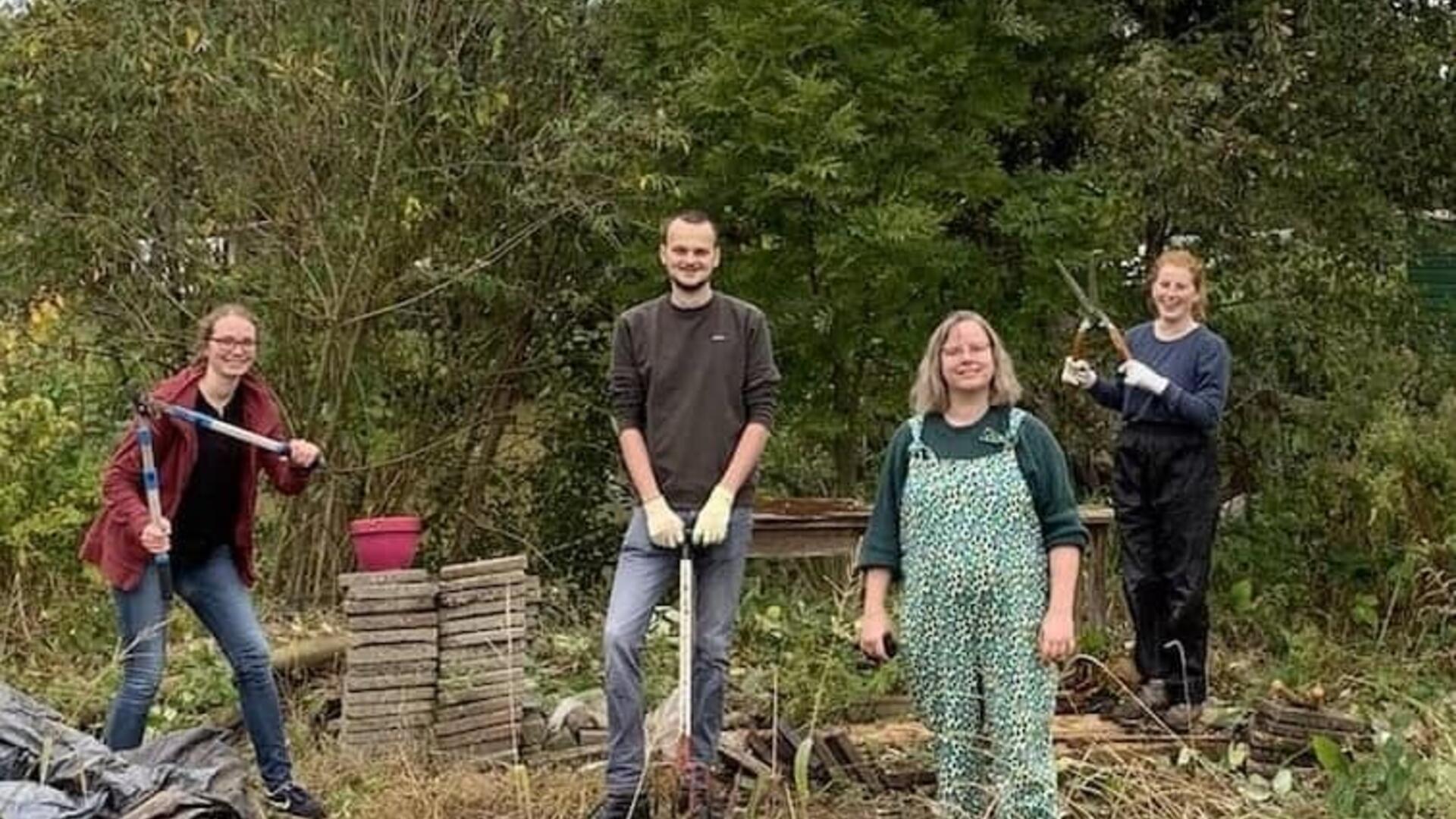 Vier vrijwilligers in een tuin aan het werk