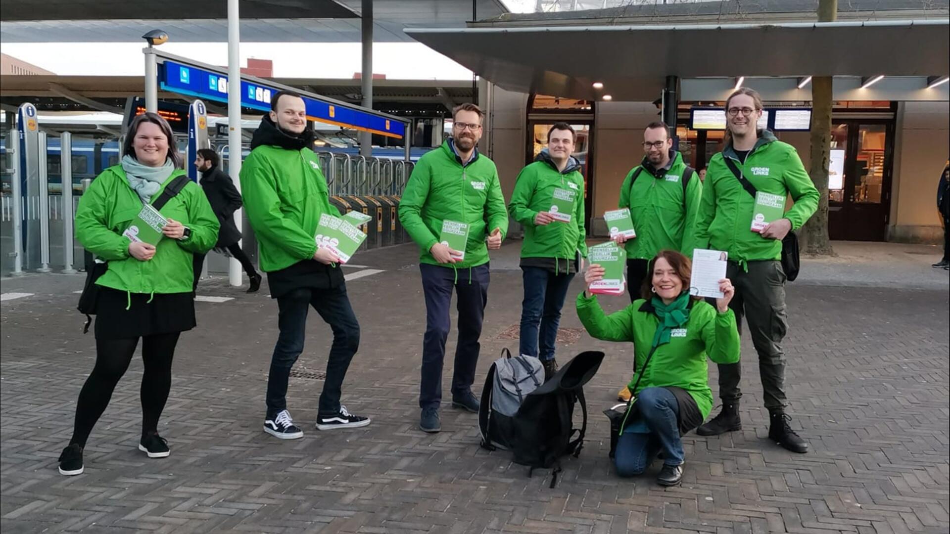 Een groep GroenLinks-vrijwilligers met groene jasjes aan bij het station van Zwolle