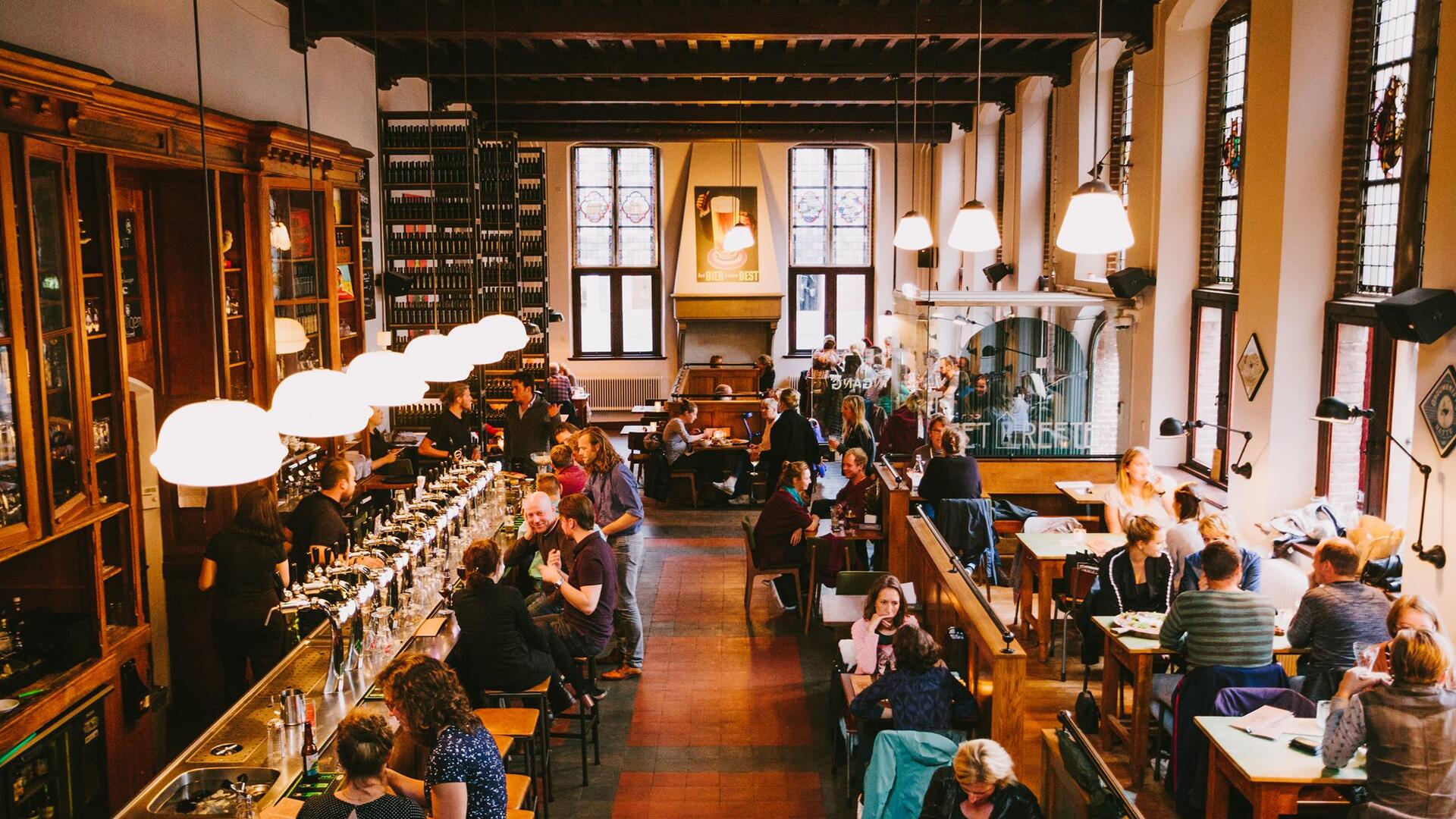 café het Refter met aan tafels en de bar groepen mensen