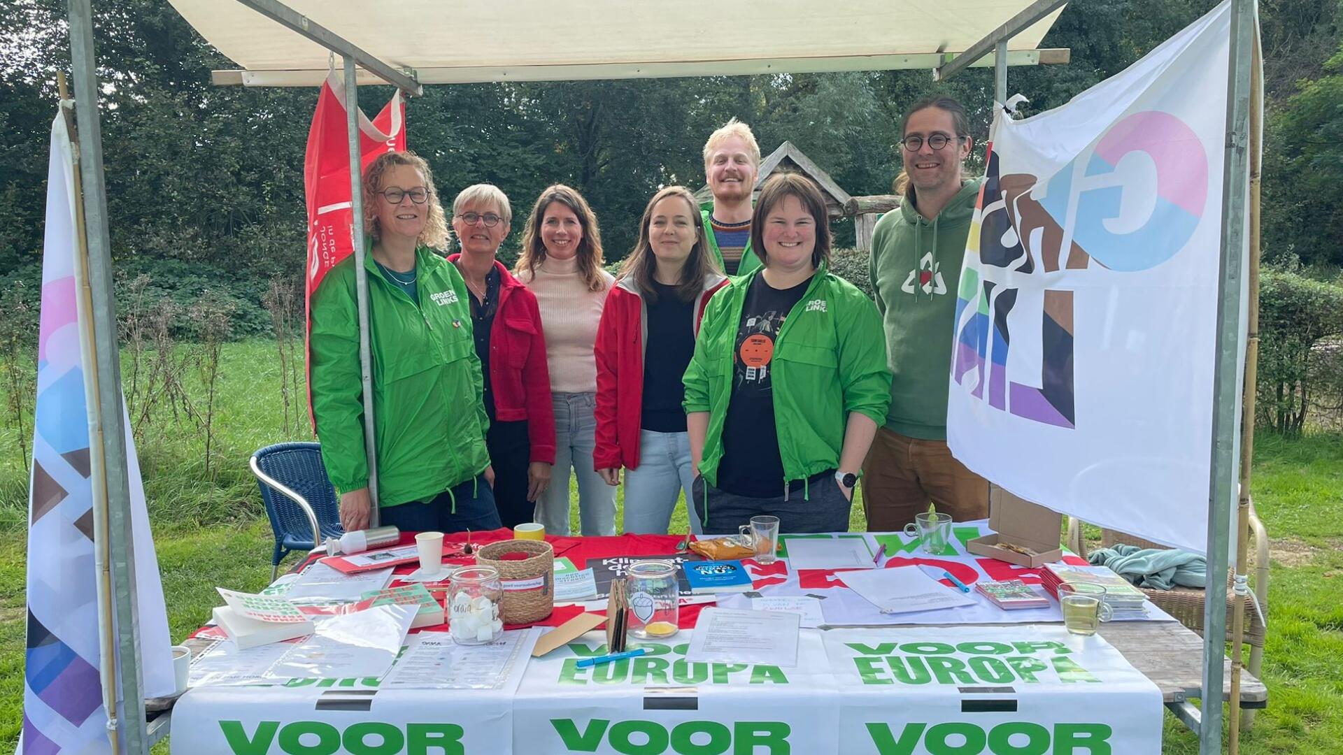 Vrijwilligers van GroenLinks en PvdA achter een marktkraam met materialen van de beide partijen